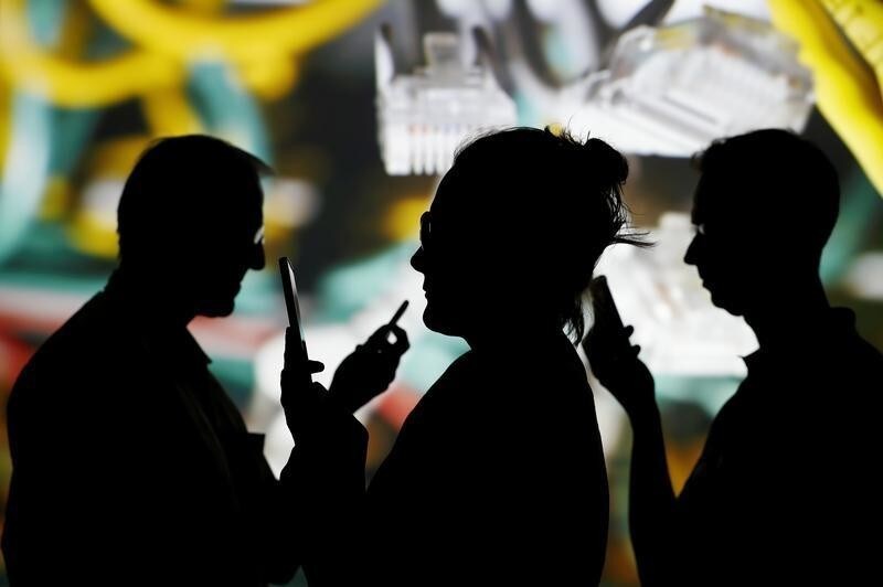 People look at data on their mobiles as background with internet wire cables on switch hub is projected in this picture illustration taken May 30, 2018.