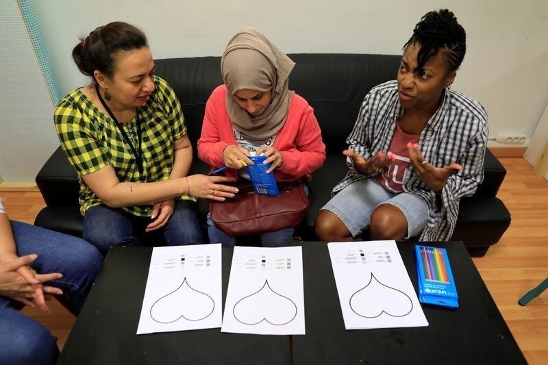 A therapist volunteer (R) from the United States reacts as Khalissa, 36, (C) from Qamishli in Syria attends the open talk at the Children and Family Protection Support Hub run by UNICEF partner Faros in Athens, Greece June 13, 2017. "Coming to the Faros centre takes people's minds off their own problems. It helps me to realise that I am not the only one to face dramatic situations... a lot of people like me have left a country that they cherish behind them," Khalissa said. "My husband has been in Germany for two years. A few days ago I had a positive response for my family reunification request, but I have no idea when I can finally leave Greece... waiting is terrible and so exhausting, I want some rest," she said. "My country was very safe and now it is completely destroyed...but if Syria becomes as before the war, I will return home. We must return home."