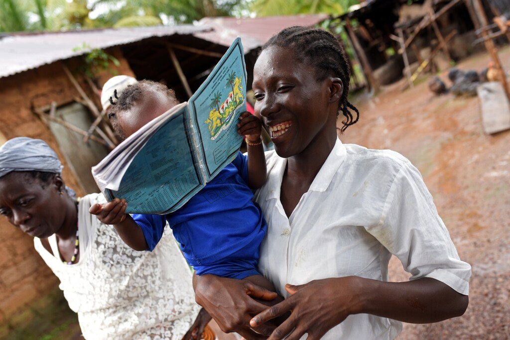 Mariatu Sesay, 15, smiles as she carries her daughter Nadia while she walks outside her house in the countryside village of Sierra Leone July 11, 2019. REUTERS/Cooper Inveen - RC18D8F12EE0