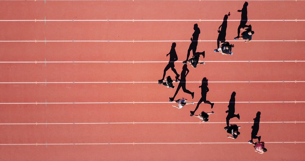 Athletes form a V shape in different lanes on a running track.