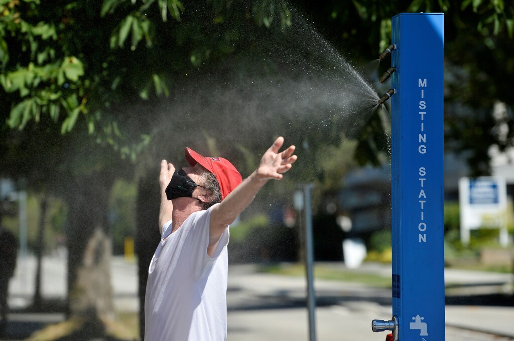 A man cools off at a misting station during the scorching weather of a heatwave in Vancouver, British Columbia, Canada