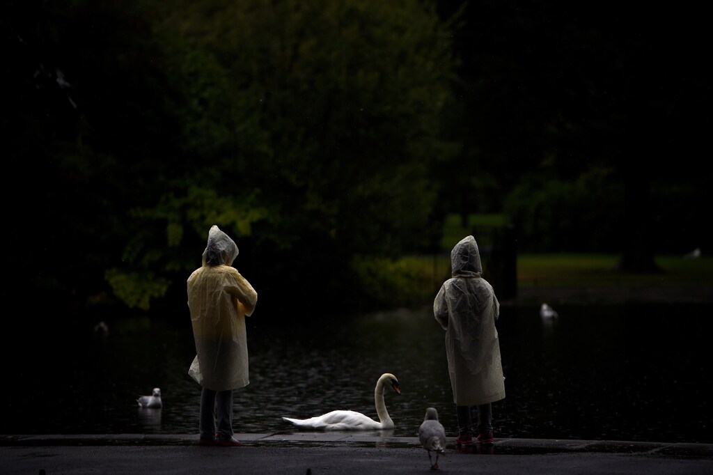 People in raincoats look at a swan in St. Stephen's green during heavy rain in Dublin, Ireland, August 14, 2017. REUTERS/Clodagh Kilcoyne SEARCH "KILCOYNE SUMMER" FOR THIS STORY. SEARCH "WIDER IMAGE" FOR ALL STORIES. - RC158D3F8DD0