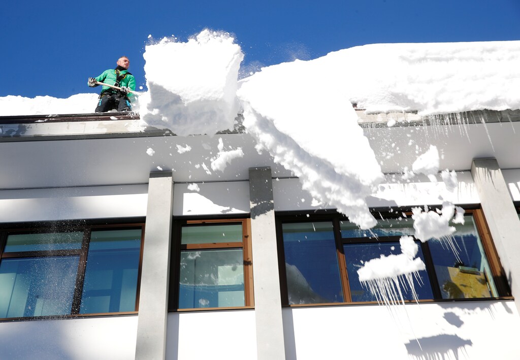 A worker removes snow from the roof of a building in Davos, Switzerland January 15, 2019. REUTERS/Arnd Wiegmann - RC13E89D4B60