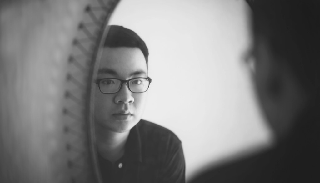 Black and white image of a man looking in a mirror