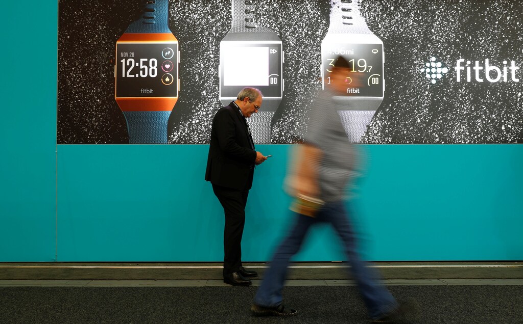 Visitors walk past an advertising billboard for Fitbit Ionic watches at the IFA Electronics Show in Berlin, Germany, September 1, 2017. REUTERS/Fabrizio Bensch - RC16DFBD5800