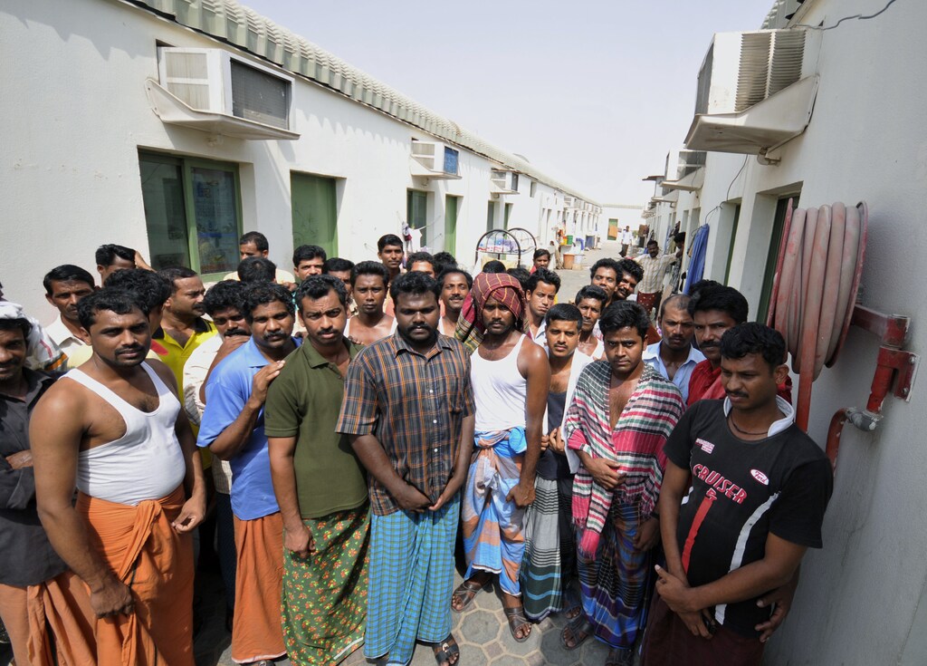 Workers stand inside the Portland labour camp in an industrial area on the outskirts of Sharjah July 20, 2010. The workers in the Sharjah camp say they have not been paid monthly wages of about 800 dirhams ($217) in six months to a year, and their families are going hungry. Abandoned by employers who left the United Arab Emirates after the Dubai economy soured, the men cannot afford to stay, but they also cannot leave. They have not been paid for months and their passports were confiscated long ago. To match Feature EMIRATES-WORKERS/ REUTERS/Jumana El Heloueh (UNITED ARAB EMIRATES - Tags: EMPLOYMENT BUSINESS) - GM1E67K1OH201