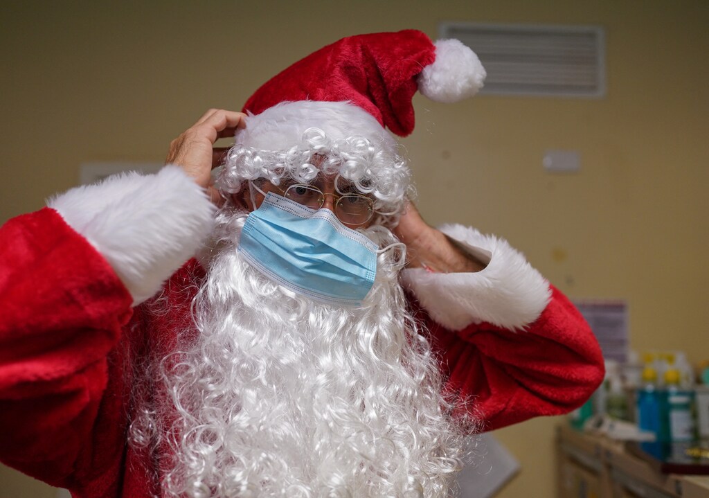 Pastor David Shrimpton, 57, known as the "flying padre" puts on a protective face mask with his Santa Claus costume before speaking to young students about Christmas at School of the Air in Broken Hill, Australia, December 8, 2021. Since 2003 Shrimpton has been flying to some of Australia's most isolated communities to talk and listen to a scattered flock. That largely stopped last year when Australia introduced some of the world's strictest COVID-19 restrictions. Now, Shrimpton is taking to the skies again. "It will be great to go out again and reconnect with these folk, reconnect with the kids and be part of their school life once again, reconnect with the adults who are living remotely and, let them know that they're not forgotten," he told Reuters. REUTERS/Loren Elliott SEARCH "ELLIOTT FLYING PASTOR" FOR THIS STORY. SEARCH "WIDER IMAGE" FOR ALL STORIES. TPX IMAGES OF THE DAY
