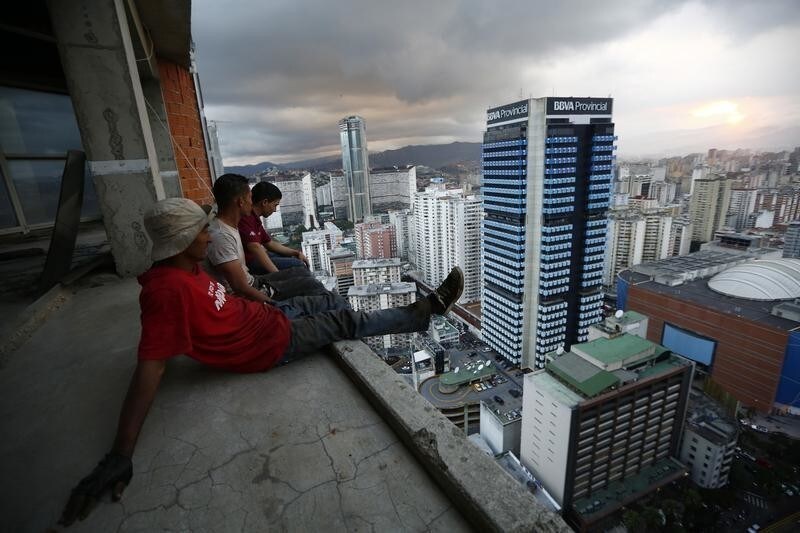 Men rest after salvaging metal on the 30th floor of the "Tower of David" skyscraper in Caracas February 3, 2014. It boasts a helicopter landing pad, glorious views of the Avila mountain range, and large balconies for weekend barbecues. Yet a 45-storey skyscraper in the center of Venezuela's capital Caracas is no five-star hotel or swanky apartment block: it is a slum, probably the highest in the world. Dubbed the "Tower of David", the building was intended to be a shining new financial center but was abandoned around 1994 after the death of its developer - banker and horse-breeder David Brillembourg - and the collapse of the financial sector. Squatters invaded the huge concrete skeleton in 2007, then-president Hugo Chavez's socialist government turned a blind eye, and now about 3,000 people call the tower their home. Picture taken February 3, 2014. REUTERS/Jorge Silva (VENEZUELA - Tags: BUSINESS SOCIETY POVERTY TPX IMAGES OF THE DAY) - GM1EA420Q7R01