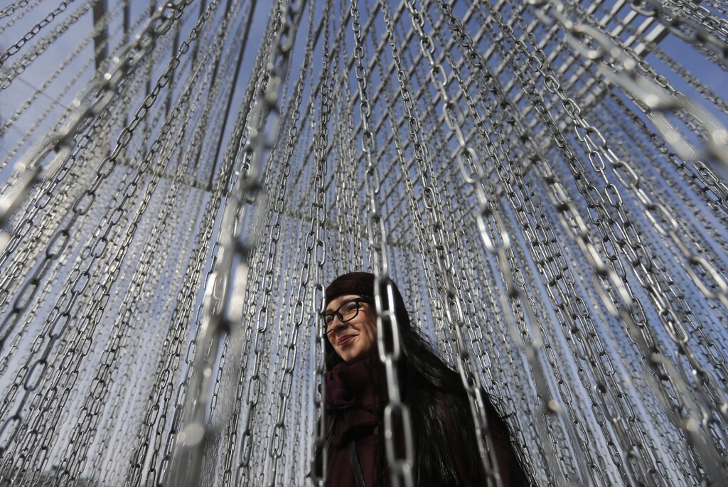 A woman walks amidst chains as she views an art installation near the Gorky Central Park of Culture and Leisure in Moscow, March 14, 2014.