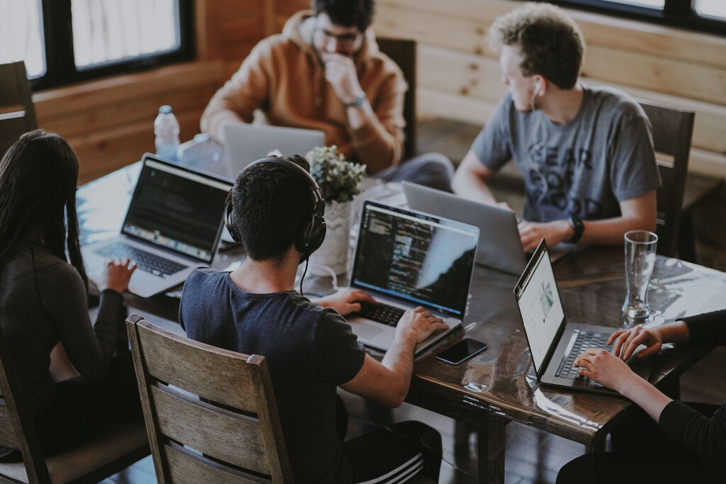 Employees sitting working on laptops around a table