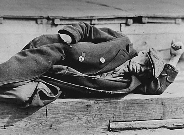 An unemployed man in an old coat is seen lying down on a pier in the New York City docks during the Great Depression, 1935. REUTERS/Lewis W Hine