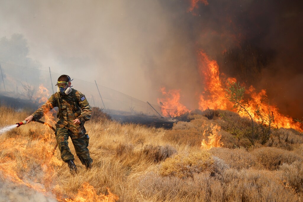 A volunteer tries to extinguish a wildfire burning in the village of Markati, near Athens, Greece, August 16, 2021.