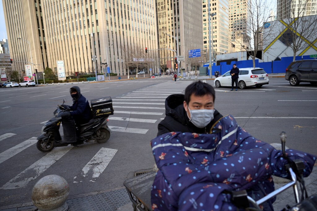 Delivery workers wearing face masks ride scooters, as the country is hit by an outbreak of the novel coronavirus, in Beijing's central business district, China February 18, 2020. REUTERS/Tingshu Wang - RC203F9M08BQ