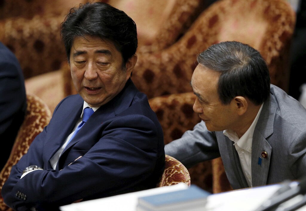 Japan's Prime Minister Shinzo Abe (L) talks with Chief Cabinet Secretary Yoshihide Suga at a lower house special committee session on security-related legislation at the parliament in Tokyo July 15, 2015. Abe faces his toughest challenge since taking office in 2012 as his ruling bloc prepares to force unpopular security bills through the lower house despite voter doubts about the legislation and a slew of other policies. REUTERS/Toru Hanai - GF10000159484