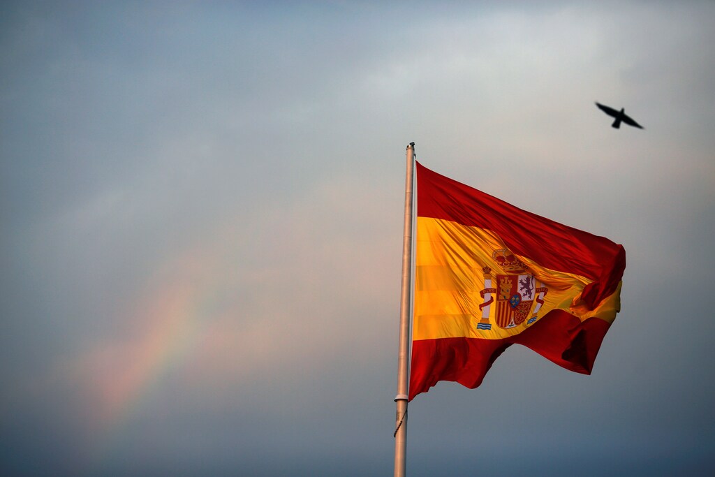 A rainbow is seen as a bird flies past a giant Spanish flag at Colon square in Madrid, Spain, July 27, 2016. Picture taken July 27, 2016. REUTERS/Susana Vera - D1BETSICFXAA