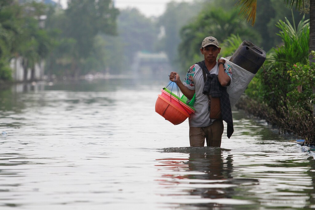 A man carries baskets through a flooded road, at an area affected by land subsidence and rising sea level in North Jakarta, Indonesia, June 5, 2020. REUTERS/Ajeng Dinar Ulfiana - RC2Y2H9Z3F92