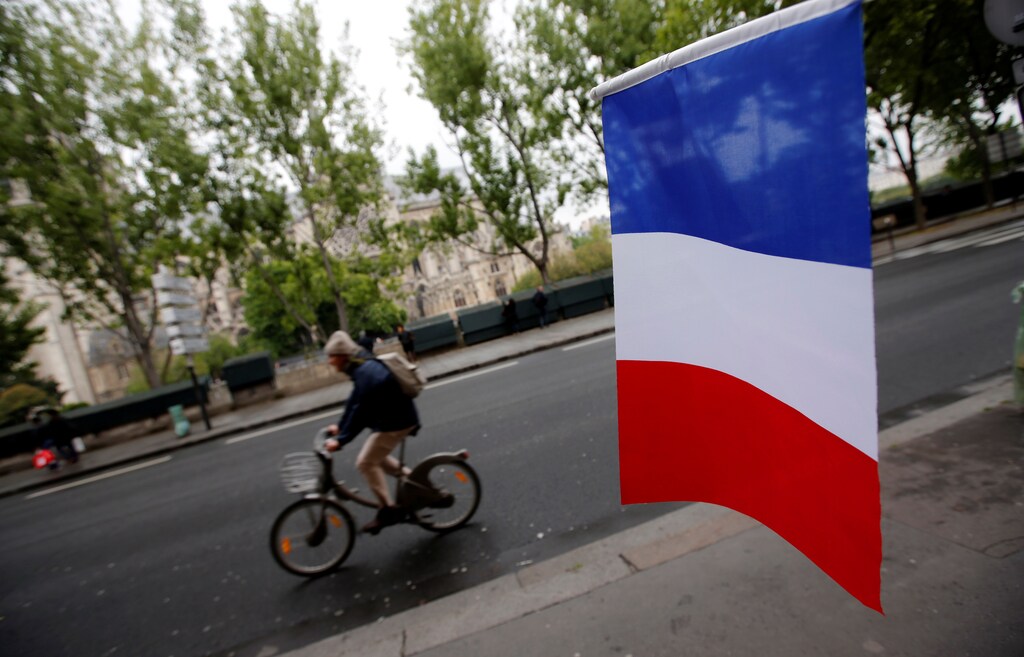 A cyclist passes a French flag on the eve of the French presidential election in Paris, France, May 6, 2017REUTERS/Jean-Paul Pelissier - RC1FF4FA7070