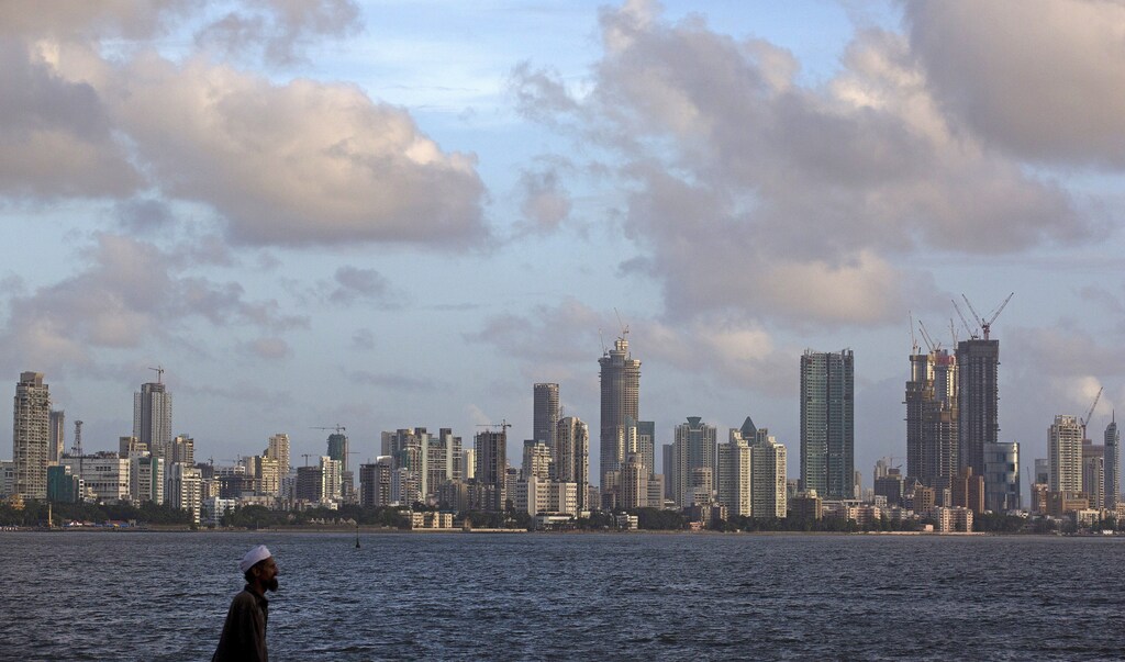 A man walks at the seafront as scattered clouds are seen over Mumbai's skyline, India, June 10, 2015. REUTERS/Danish Siddiqui - GF10000122941