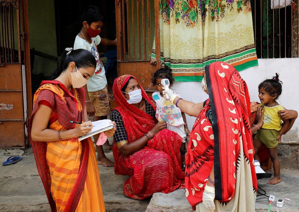 A healthcare worker checks the temperature of a child during a door-to-door surveillance to safeguard children amidst the spread of the coronavirus disease (COVID-19), at a village on the outskirts of Ahmedabad, India, June 9, 2021. REUTERS/Amit Dave - RC2SWN9LZF64