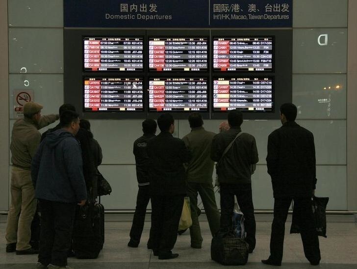 Passengers look at screens displaying flight information regarding delayed or cancelled flights at Beijing airport January 3, 2010. Heavy snow hit Beijing on Sunday stranding thousands of passengers at the Chinese capital's main airport and casting an unusual quiet over normally busy streets as people stayed out of the freezing weather. REUTERS/David Gray (CHINA - Tags: SOCIETY ENVIRONMENT TRANSPORT)