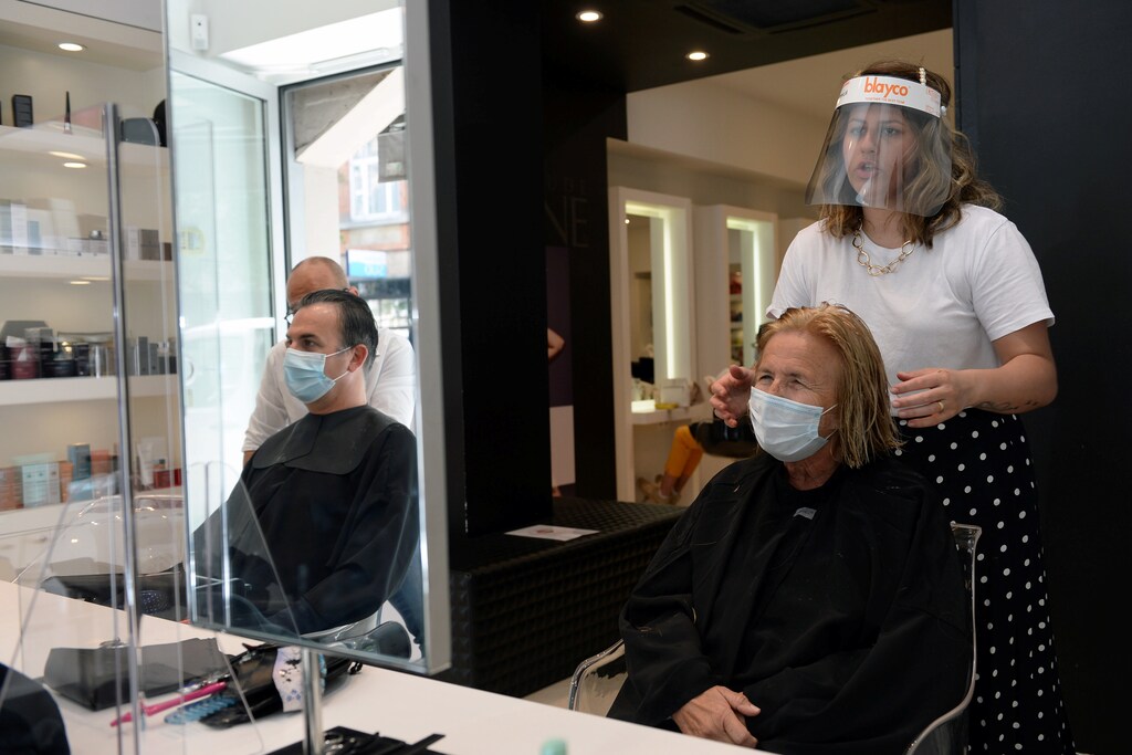 A hairdresser wearing a protective face mask cuts the hair of a customer following the outbreak of the coronavirus disease (COVID-19) in Brussels, Belgium, May 18, 2020.REUTERS/Johanna Geron - RC22RG9BQKG2