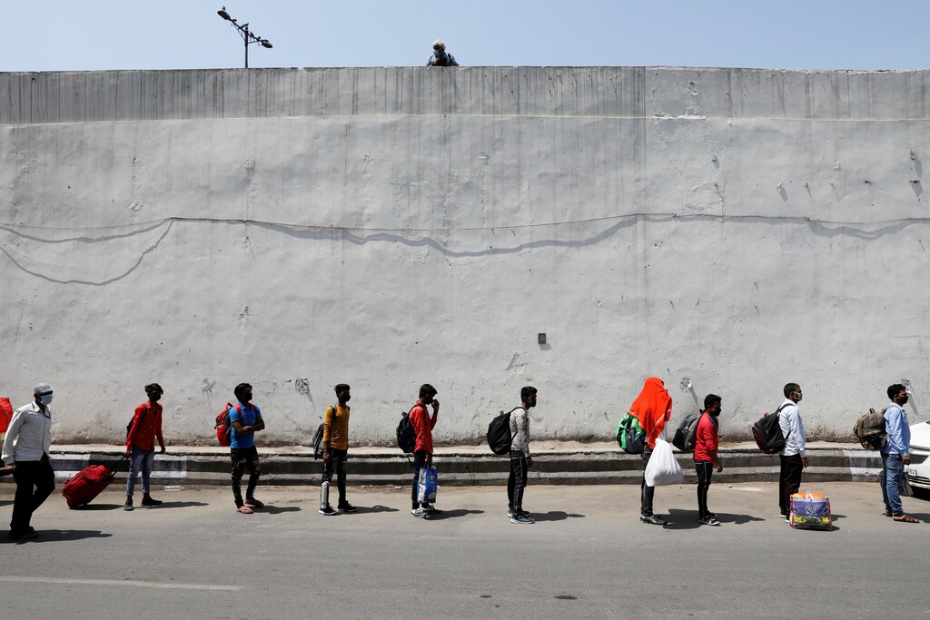 People carrying their belongings queue outside a railway station to board trains that will take them to their home states, after India announced a limited reopening of its giant rail network following a nearly seven-week lockdown to slow the spreading of the coronavirus disease (COVID-19), in New Delhi, India, May 12, 2020.