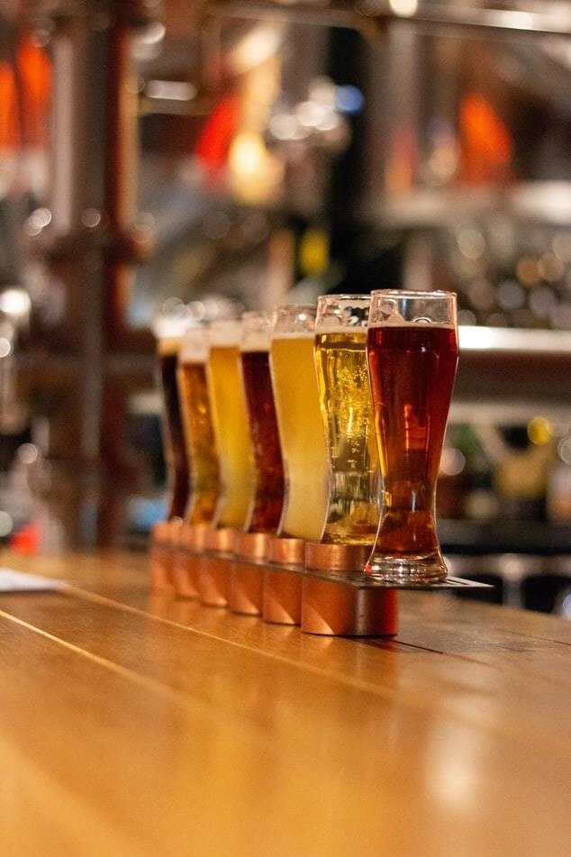 7 beers placed on a bar top.