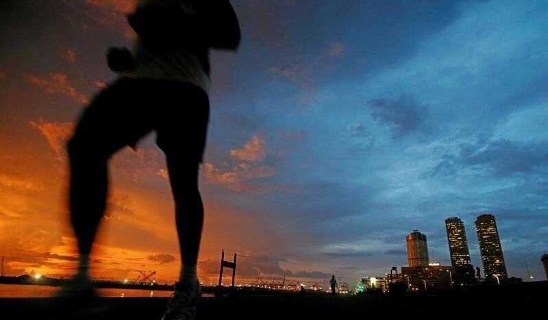 Financial district of Colombo is seen as a man runs along a path in front of the China invested Colombo Port City construction site in Colombo, Sri Lanka November 22, 2017. REUTERS/Dinuka Liyanawatte - RC1DEDEB6E50