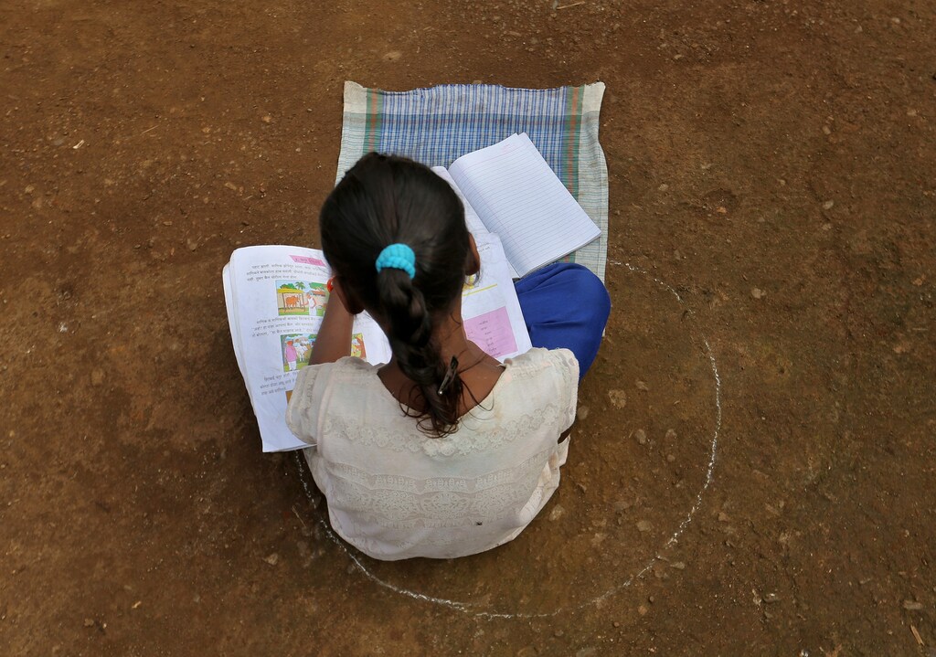 A girl, who has missed her online classes due to a lack of internet facilities, sits on the ground in a circle drawn with chalk to maintain safe distance as she listens to pre-recorded lessons over loudspeakers, after schools were closed following the coronavirus disease (COVID-19) outbreak, in Dandwal village in the western state of Maharashtra, India, July 23, 2020. Picture taken July 23, 2020. REUTERS/Prashant Waydande - RC2P6I9O9AW2