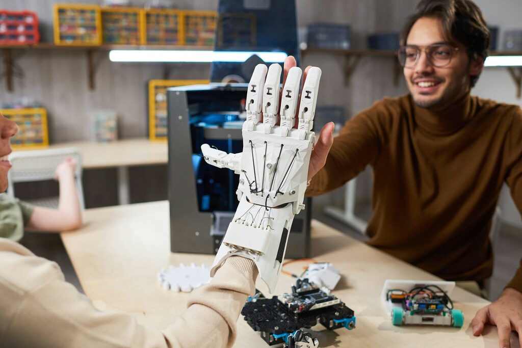 A man in a lab setting puts his hand against a robotic hand: Scaling innovation requires a supportive ecosystem