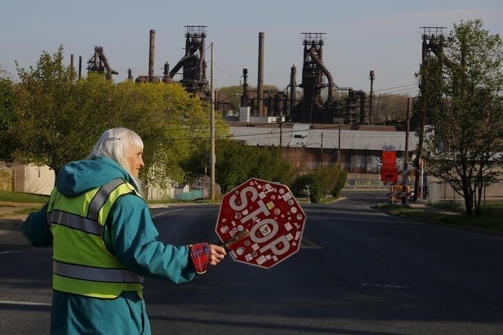 Seventy-six-year-old crossing guard June Young helps pedestrians through an intersection she has worked for 32 years, with the blast furnaces from the now-closed Bethlehem Steel mill behind her, in Bethlehem, Pennsylvania, U.S. April 21, 2016. Young's father and two brothers all worked at the steel mill, her father from the age of eighteen until he retired at the age of sixty-two. REUTERS/Brian Snyder SEARCH "BETHLEHEM STEEL" FOR THIS STORY. SEARCH "THE WIDER IMAGE" FOR ALL STORIES