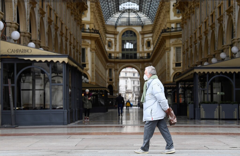 A man wearing a protective face mask walks past a deserted Galleria Vittorio Emanuele II, on the third day of an unprecedented lockdown across of all Italy imposed to slow the outbreak of coronavirus, in Milan, Italy, March 12, 2020. REUTERS/Flavio Lo Scalzo - RC2CIF9VQSD5