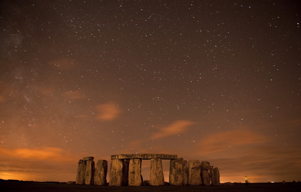 A meteor streaks past stars in the night sky over Stonehenge on Salisbury Plain, southern England August 12, 2010. The Perseid meteor shower is sparked every August when the Earth passes through a stream of space debris left by comet Swift-Tuttle. Picture taken using a long exposure. REUTERS/Kieran Doherty (BRITAIN - Tags: ENVIRONMENT SOCIETY) - GM1E68D0VMN01