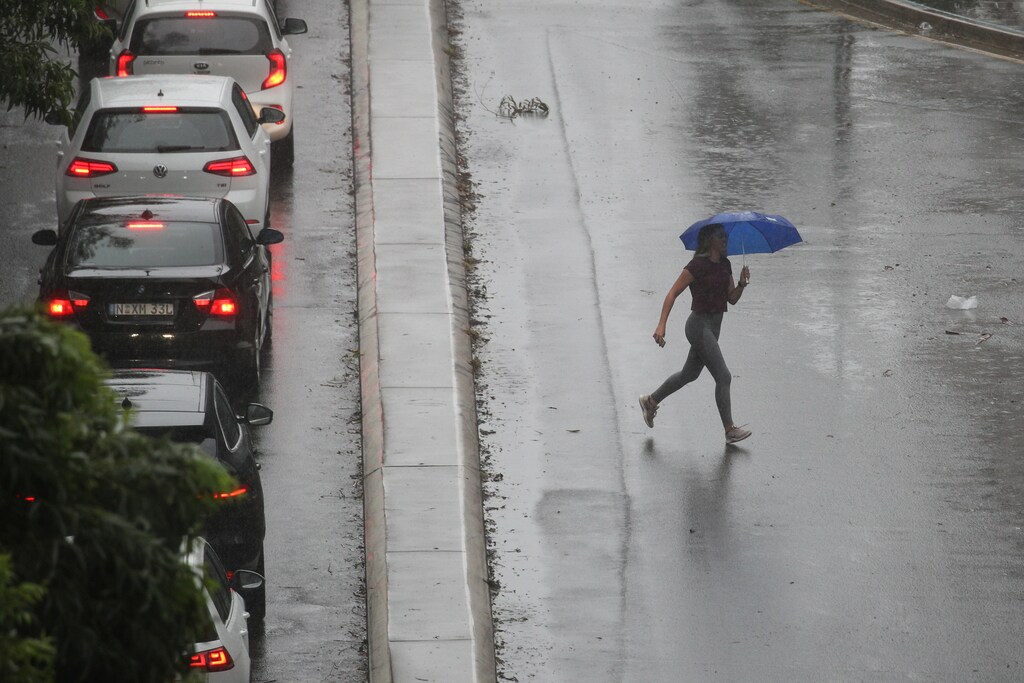 A pedestrian braves strong wind and rain in Sydney, New South Wales, Australia, February 9, 2020. REUTERS/Loren Elliott - RC2PWE9W96OT