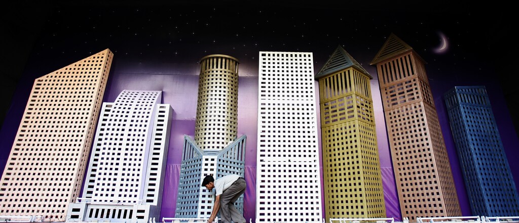 A worker adjusts decorative lights on a model of skyscrapers representing the future of Mumbai city at an enclosure to celebrate 'Ganesh Chaturthi', a festival of the Hindu God Ganesh in Mumbai September 14, 2007. The festival begins on Saturday. REUTERS/Arko Datta (INDIA) - GM1DWDPQLCAA