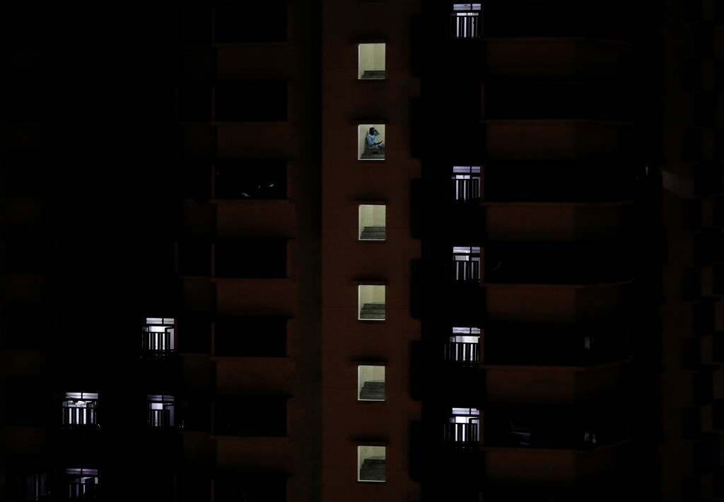 A migrant worker sits outside his dormitory room, amid the coronavirus disease (COVID-19) outbreak in Singapore April 30, 2020. REUTERS/Edgar Su - RC2YEG91CQYI