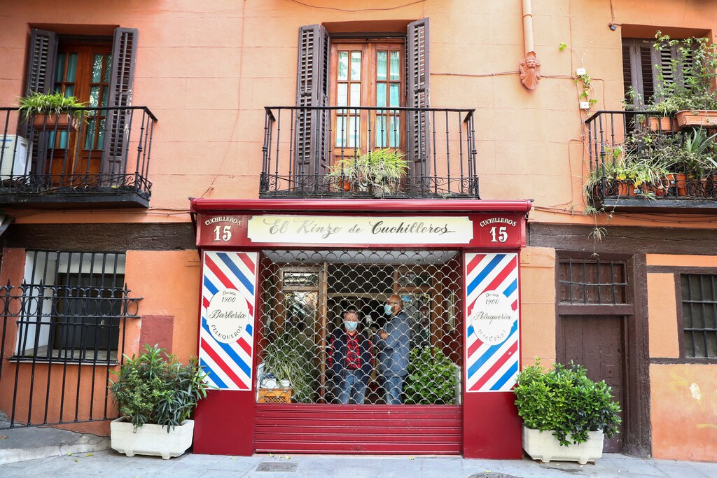 Alfonso Sanchidrián y Rafael López, propietarios de la peluquería más antigua de Madrid, usan máscaras de protección facial mientras están de pie en su negocio cerrado, después de que el Gobierno español anunciara que las peluquerías y otros negocios que operan con cita previa podrán reabrir a partir del 4 de mayo, en medio del brote de la enfermedad coronavirus (COVID-19) en Madrid, España, el 29 de abril de 2020.