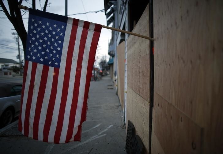 An American flag hangs on the front of a row of boarded up buildings, destroyed by flooding from the storm surge during Hurricane Sandy, in Sea Bright, New Jersey, November 15, 2012. REUTERS/Chip East (UNITED STATES - Tags: ENVIRONMENT)