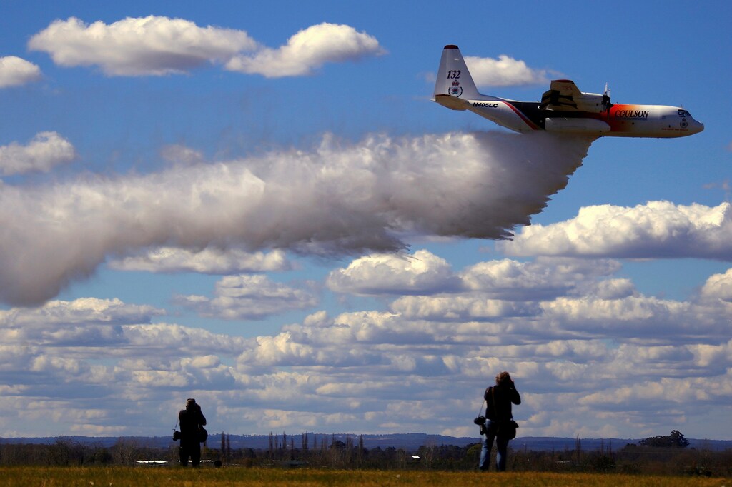 Photographers take photographs of the Large Air Tanker (LAT) C-130 Hercules, also known as Thor, as it drops a load of around 15,000 litres during a display by the Rural Fire Service ahead of the bushfire season at RAAF Base Richmond Sydney, Australia, September 1, 2017. REUTERS/David Gray TPX IMAGES OF THE DAY - RC1477FAFED0