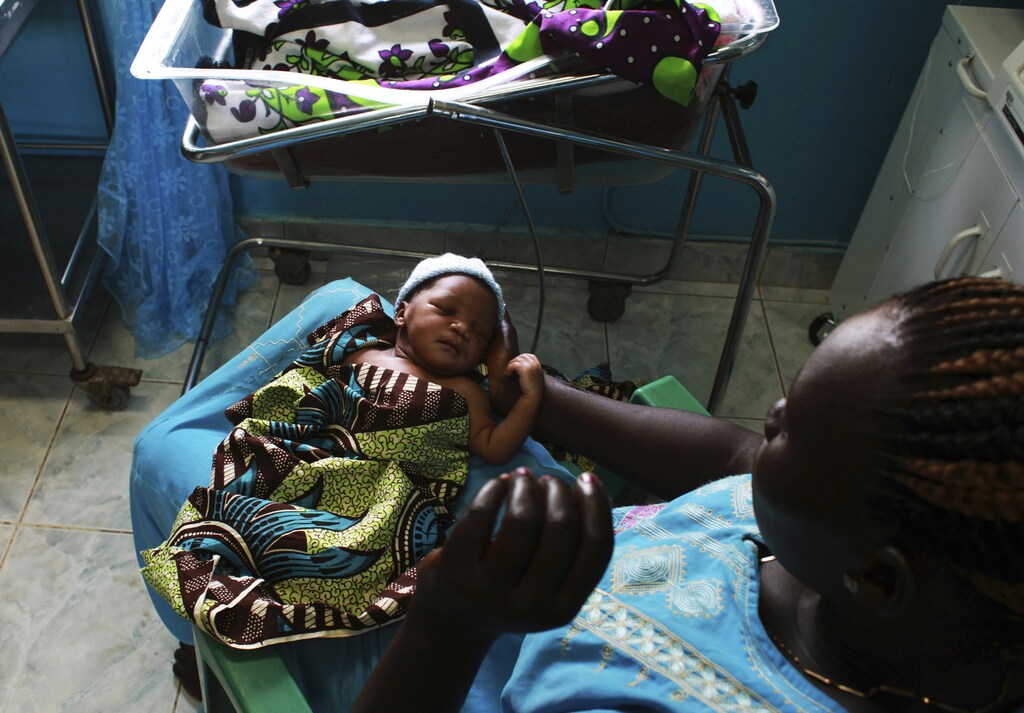 A woman holds her newborn baby in a nursery in the Juba Teaching Hospital in Juba April 3, 2013. Very few births in South Sudan, which has the highest maternal mortality rate in the world at 2,054 per 100,000 live births, are assisted by trained midwives, according to the UNDP's website. Picture taken April 3, 2013. REUTERS/Andreea Campeanu (SOUTH SUDAN - Tags: SOCIETY HEALTH TPX IMAGES OF THE DAY) - RTXY7Q8