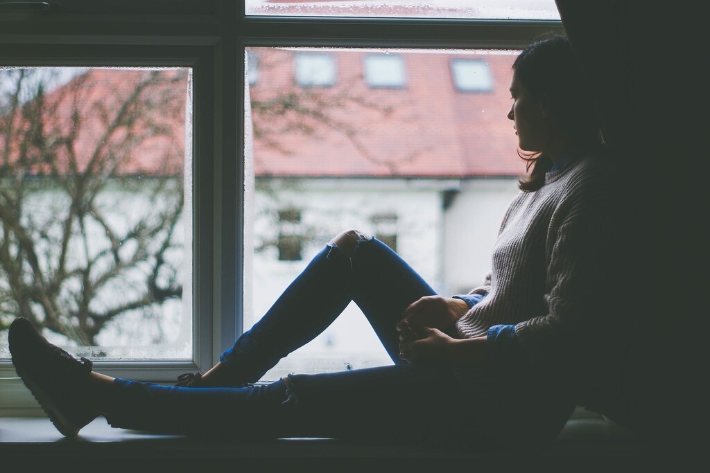 image of a young woman looking sadly out of a window