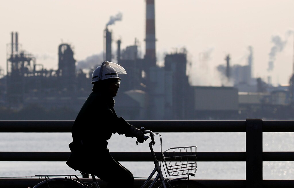 A worker cycles near a factory at the Keihin industrial zone in Kawasaki, Japan, November 15, 2017. REUTERS/Toru Hanai - RC19CAF40440