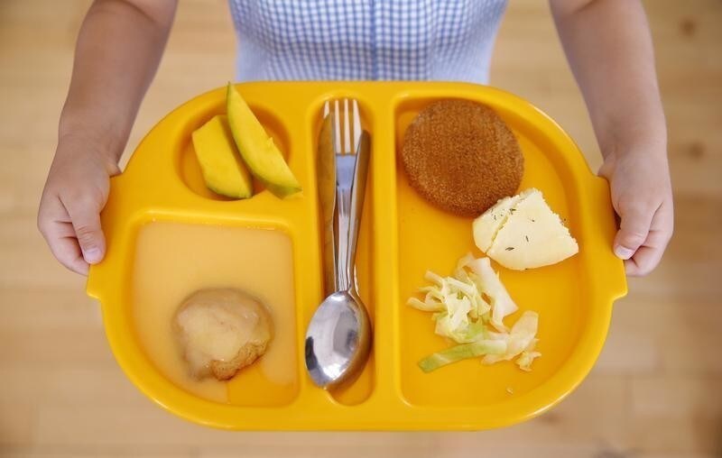 A student carries her lunch tray at Salusbury Primary School in northwest London June 11, 2014. This September, a new government scheme plans to give free meals to all reception, year 1 and 2 students registered in England's state-funded schools. Local media reports that this will amount to saving families about ?400 a year per child. REUTERS/Suzanne Plunkett (BRITAIN - Tags: EDUCATION SOCIETY FOOD TPX IMAGES OF THE DAY) - GM1EA6B1O2M01