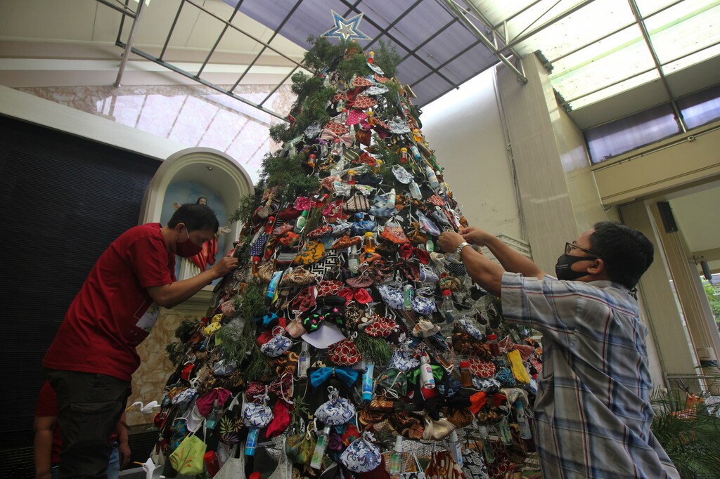 Men decorate a Christmas tree with masks and hand sanitizers at a church in Surabaya, East Java Province, Indonesia, December 16, 2020, Picture taken December 16, 2020. Antara Foto/Didik Suhartono/via REUTERS ATTENTION EDITORS - THIS IMAGE WAS PROVIDED BY THIRD PARTY. MANDATORY CREDIT. INDONESIA OUT. - RC27QK917AFD