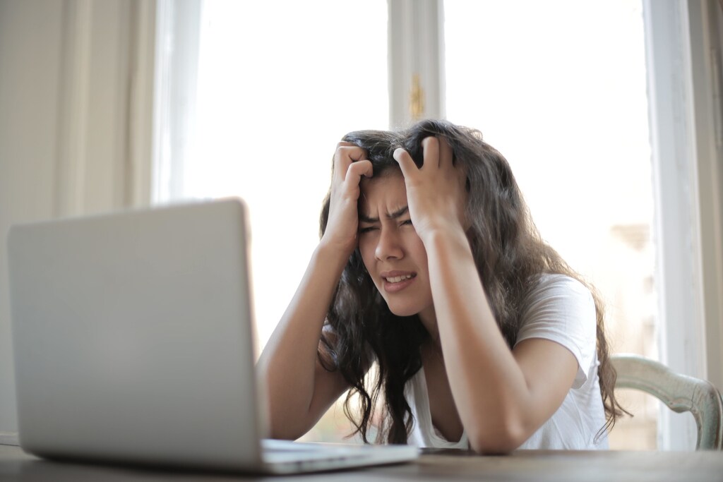 A woman feeling stressed while looking at a computer screen.