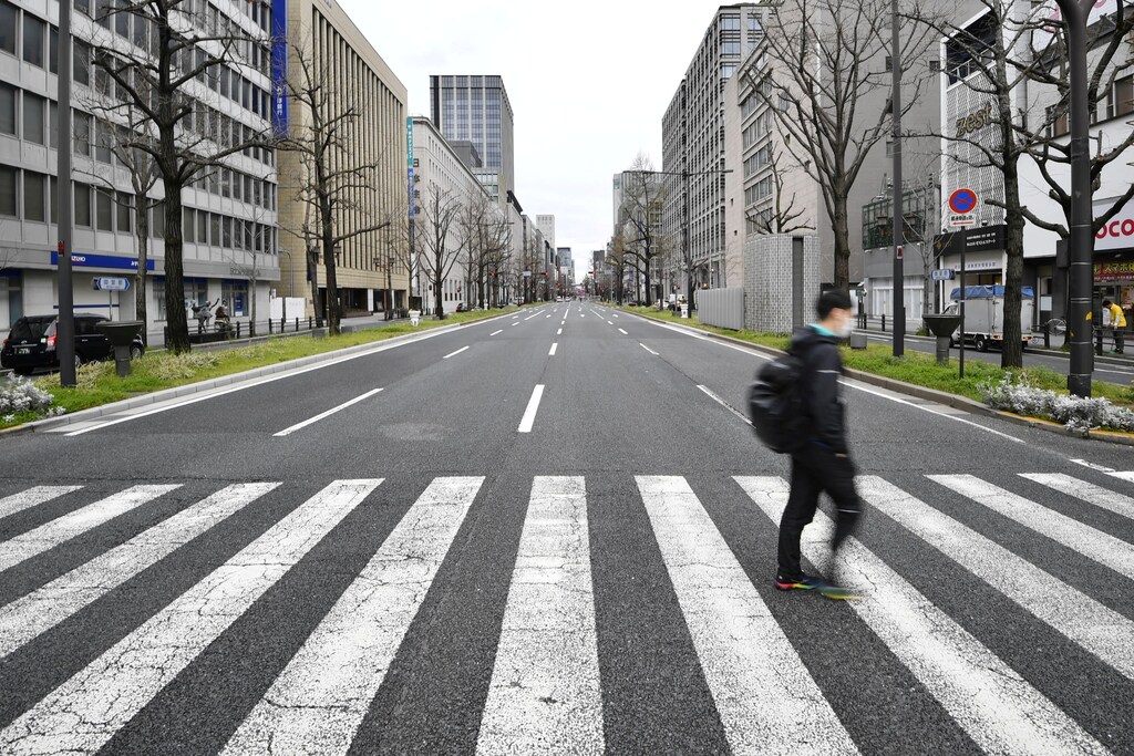 A man wearing a protective face mask, following an outbreak of the coronavirus disease (COVID-19), walks on a nearly empty street during the first weekend after Osaka local government urged the residents to stay indoors in a bid to keep a coronavirus from spreading, in Osaka, western Japan March 28, 2020, in this photo taken by Kyodo. Mandatory credit Kyodo/via REUTERS ATTENTION EDITORS - THIS IMAGE WAS PROVIDED BY A THIRD PARTY. MANDATORY CREDIT. JAPAN OUT. NO COMMERCIAL OR EDITORIAL SALES IN JAPAN. - RC2VSF99ON2D