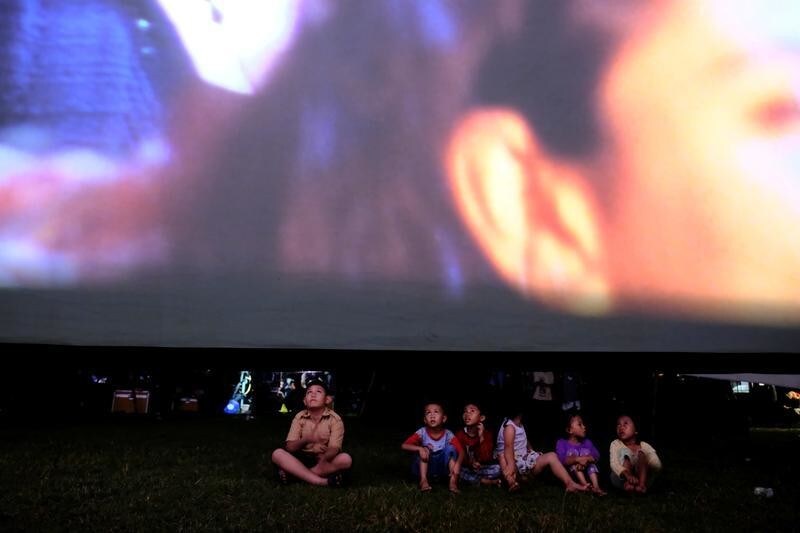 Children sit in a soccer field watching films, during a wedding party in Tangerang, Indonesia, April 15, 2017. REUTERS/Beawiharta SEARCH "BEAWIHARTA CINEMA" FOR THIS STORY. SEARCH "WIDER IMAGE" FOR ALL STORIES. TPX IMAGES OF THE DAY. - RC119703BB70