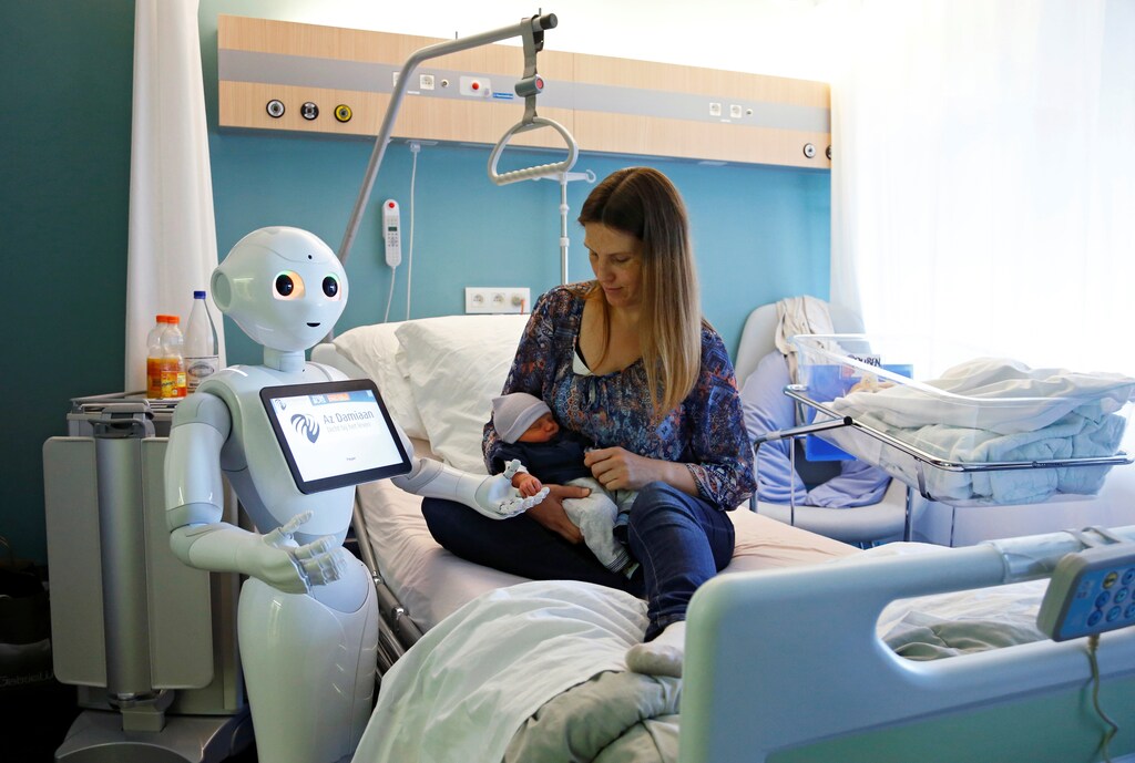 New recruit "Pepper" the robot, a humanoid robot designed to welcome and take care of visitors and patients, holds the hand of a new born baby next to his mother at AZ Damiaan hospital in Ostend, Belgium June 16, 2016. REUTERS/Francois Lenoir TPX IMAGES OF THE DAY - D1AETKFZXJAA