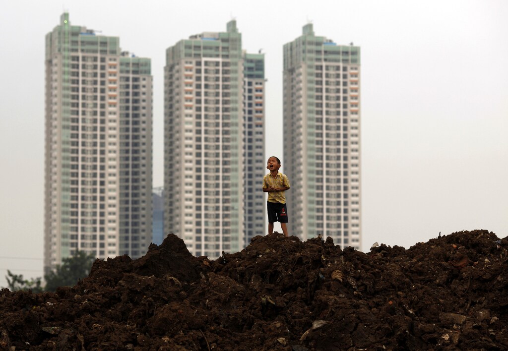 A child stands near a new apartment complex in Jakarta July 9, 2009. Indonesia's President Susilo Bambang Yudhoyono said on Thursday, a day after his landslide re-election, that he would spur growth in Southeast Asia's biggest economy to a target of 4-4.5 percent in 2009 as interest rates fall to 6 percent by year-end. REUTERS/Beawiharta (INDONESIA POLITICS ELECTIONS) - RTR25HEX
