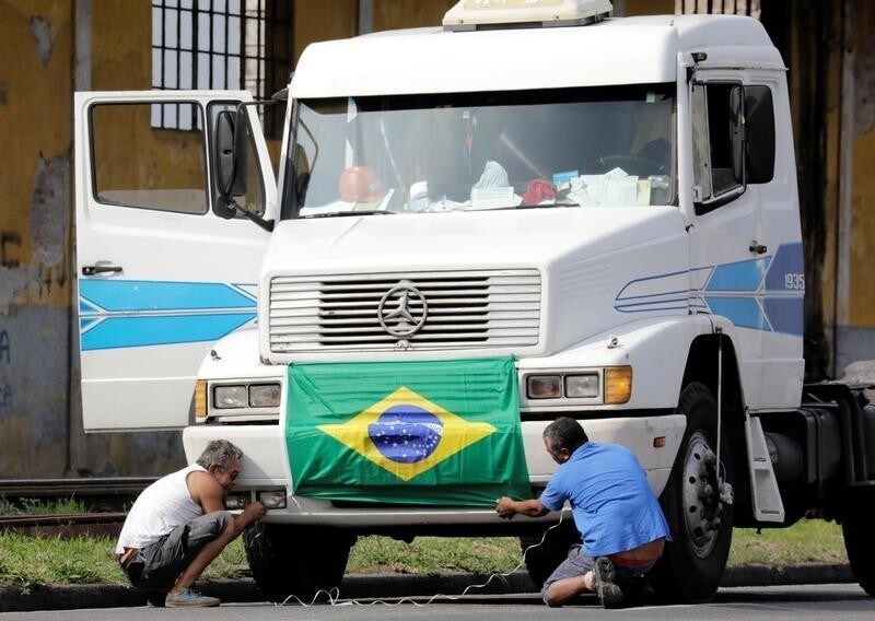 Truck drivers arrange a national flag in front of their truck to attend a protest against high diesel prices, near the port of Santos in Santos, Brazil May 23, 2018.